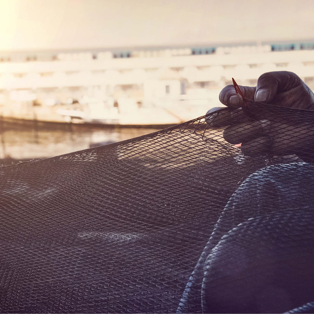 Fishermen working with fishing nets on a dock at sunset