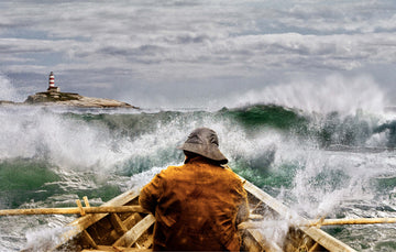Fisherman in rowboat in rough waters with lighthouse on the horizon