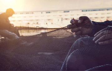 Fishermen working with fishing nets on a dock at sunset