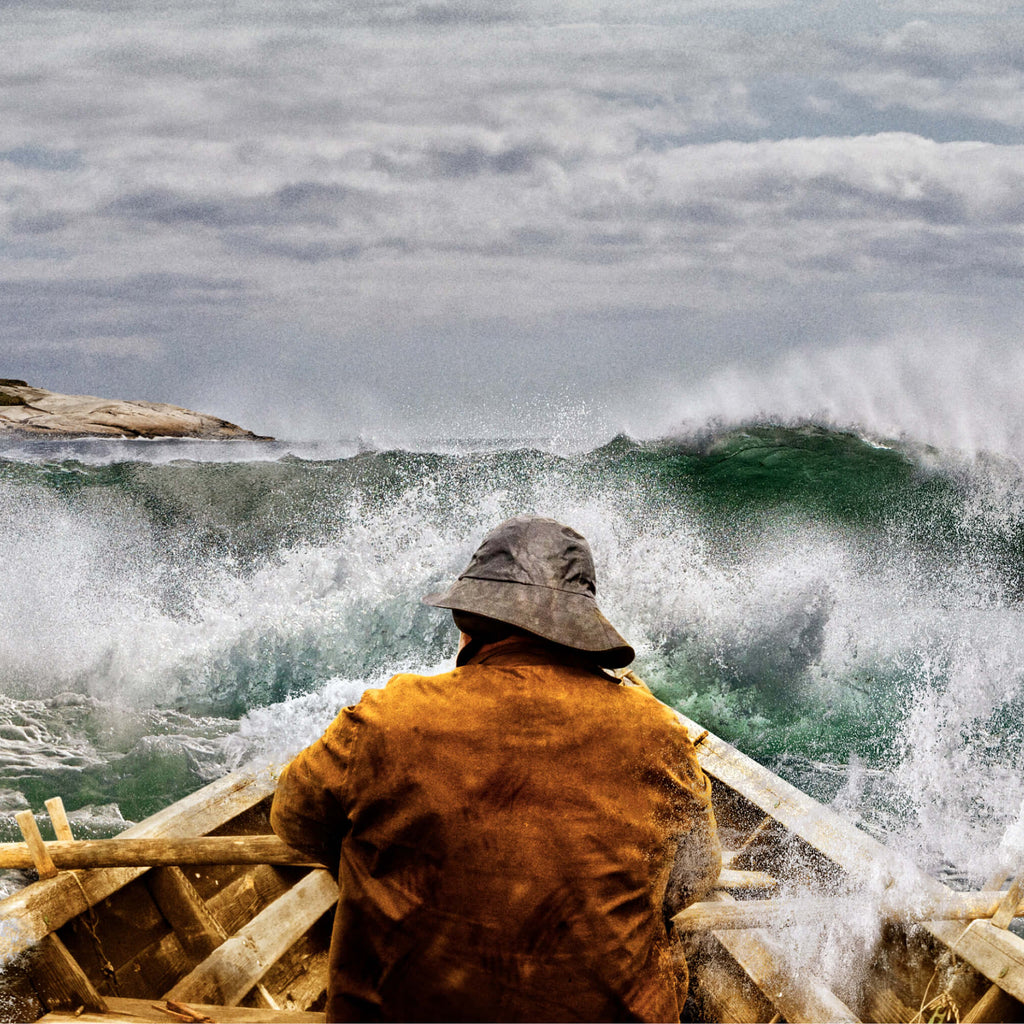 Fisherman in rowboat in rough waters with lighthouse on the horizon
